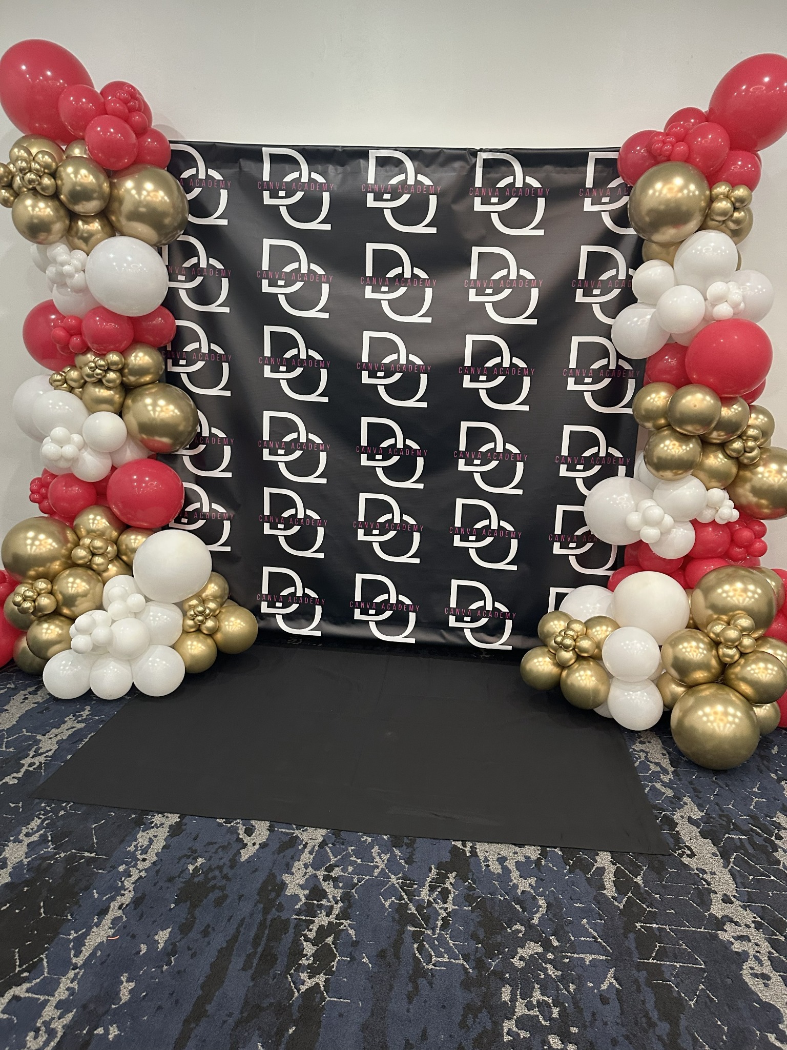 A DQ Canva Academy photo backdrop framed by red, white and gold balloon columns at the Orlando meetup