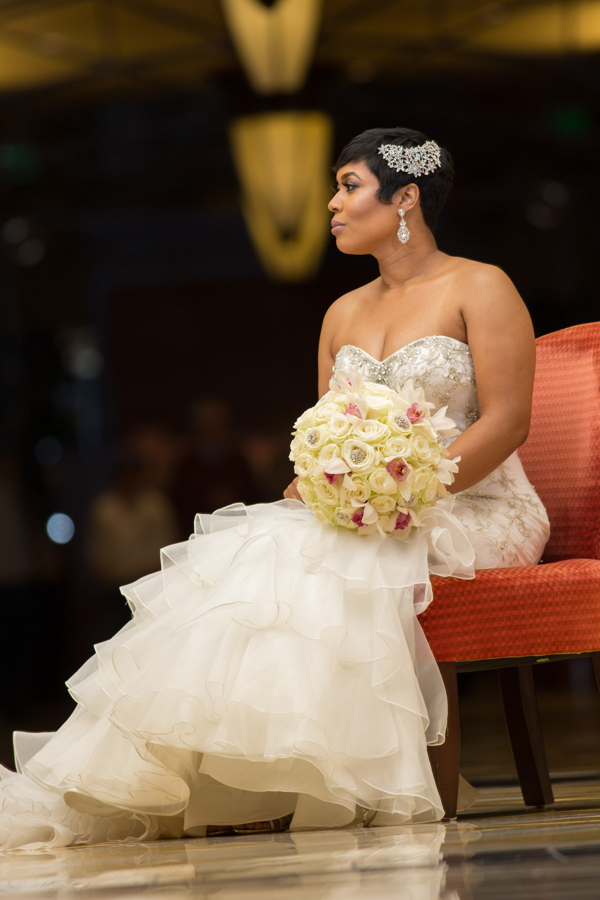 A bride in an ivory gown holding a bouquet of white roses and orchids
